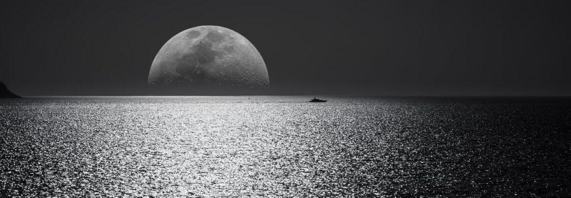 white and black moon with black skies and body of water photography during night time