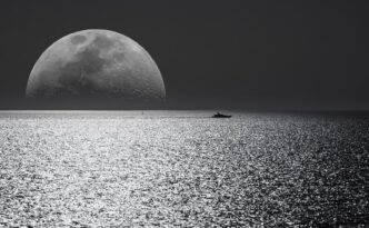 white and black moon with black skies and body of water photography during night time